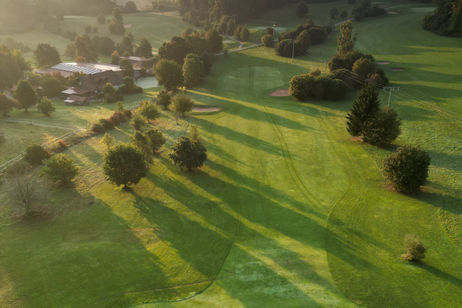 Fairway der Golfanlage Gerhelm im Morgenlicht, lange Schatten der Bäume